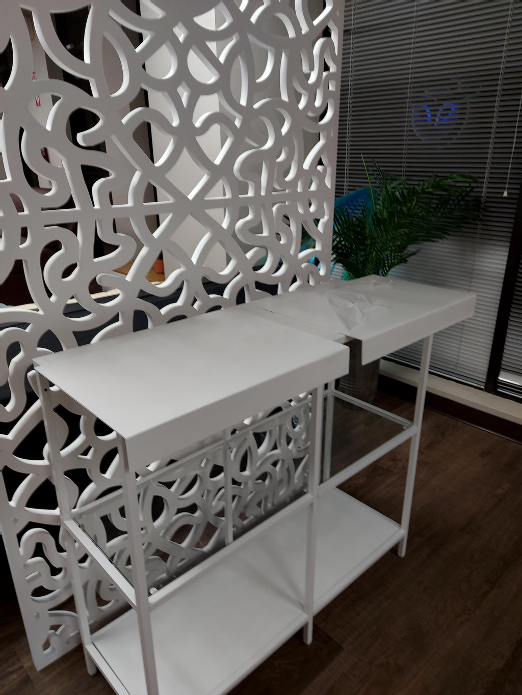White decorative screen with a shelf against a dark wall
